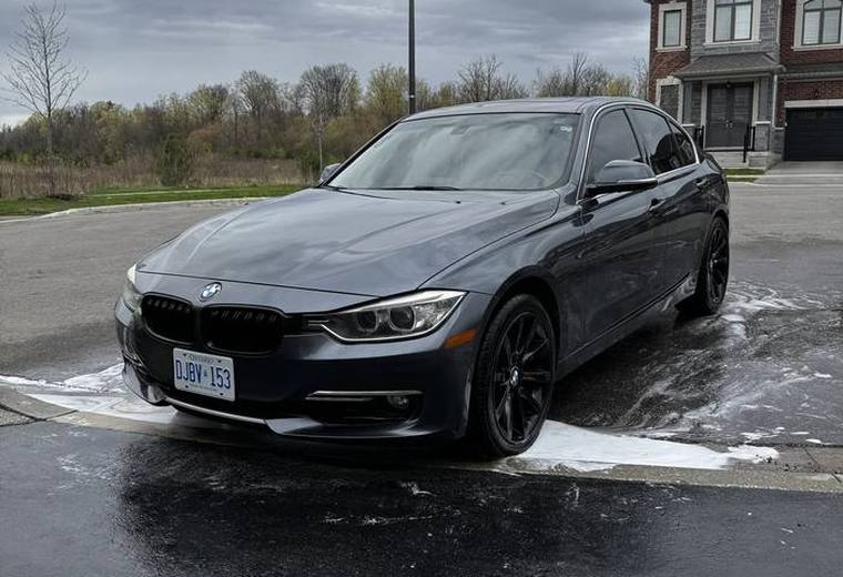 Grey BMW 3 Series parked with wash foam on pavement