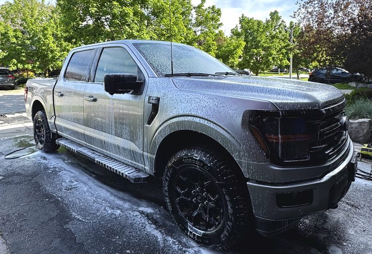 Ford F-150 pickup covered in wash foam on a sunny driveway