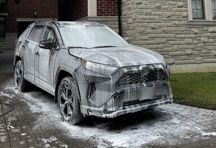 Toyota RAV4 covered in snow foam outside a stone house