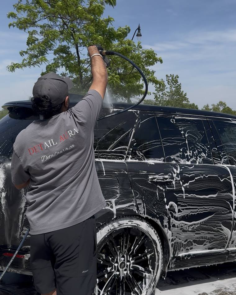 Karam foam washing an SUV on site in a Detail Aura shirt